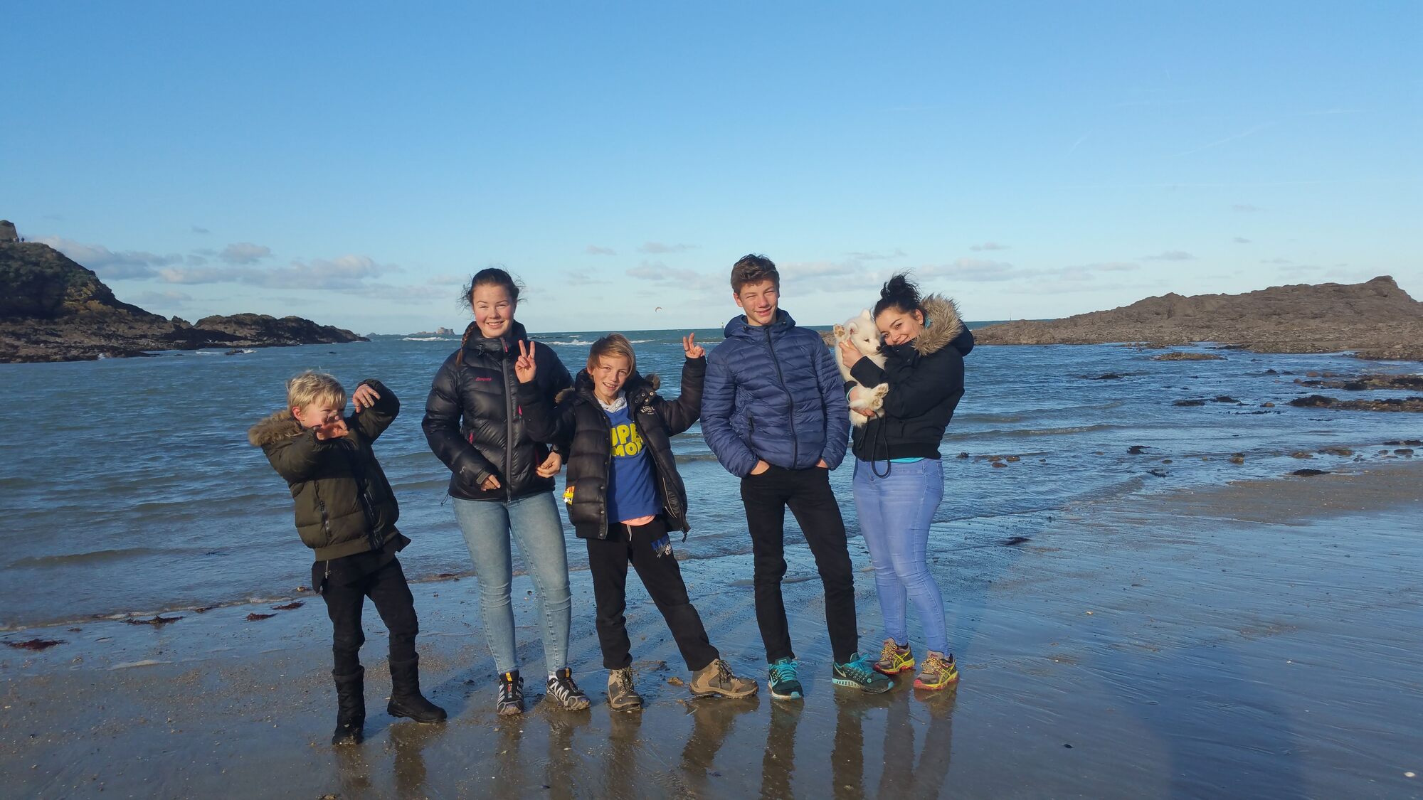 Groupe de jeunes souriants profitant d’une journée à la plage pendant un échange linguistique — symbole d’amitié, de découverte et d’aventure culturelle avec Coco Swap