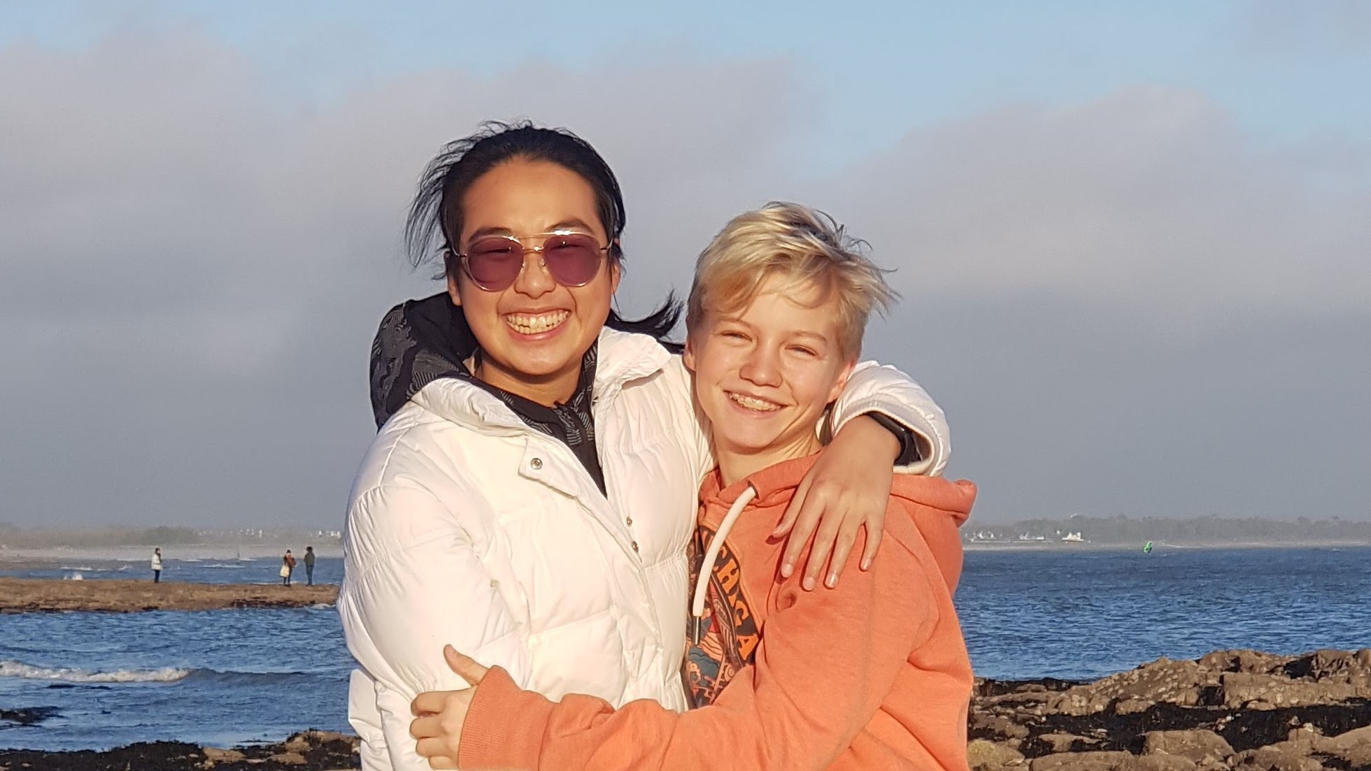 SamYi de Hong Kong et Marin de France souriant ensemble sur la plage, symbole de confiance, de respect et d’amitié entre cultures sur Coco Swap