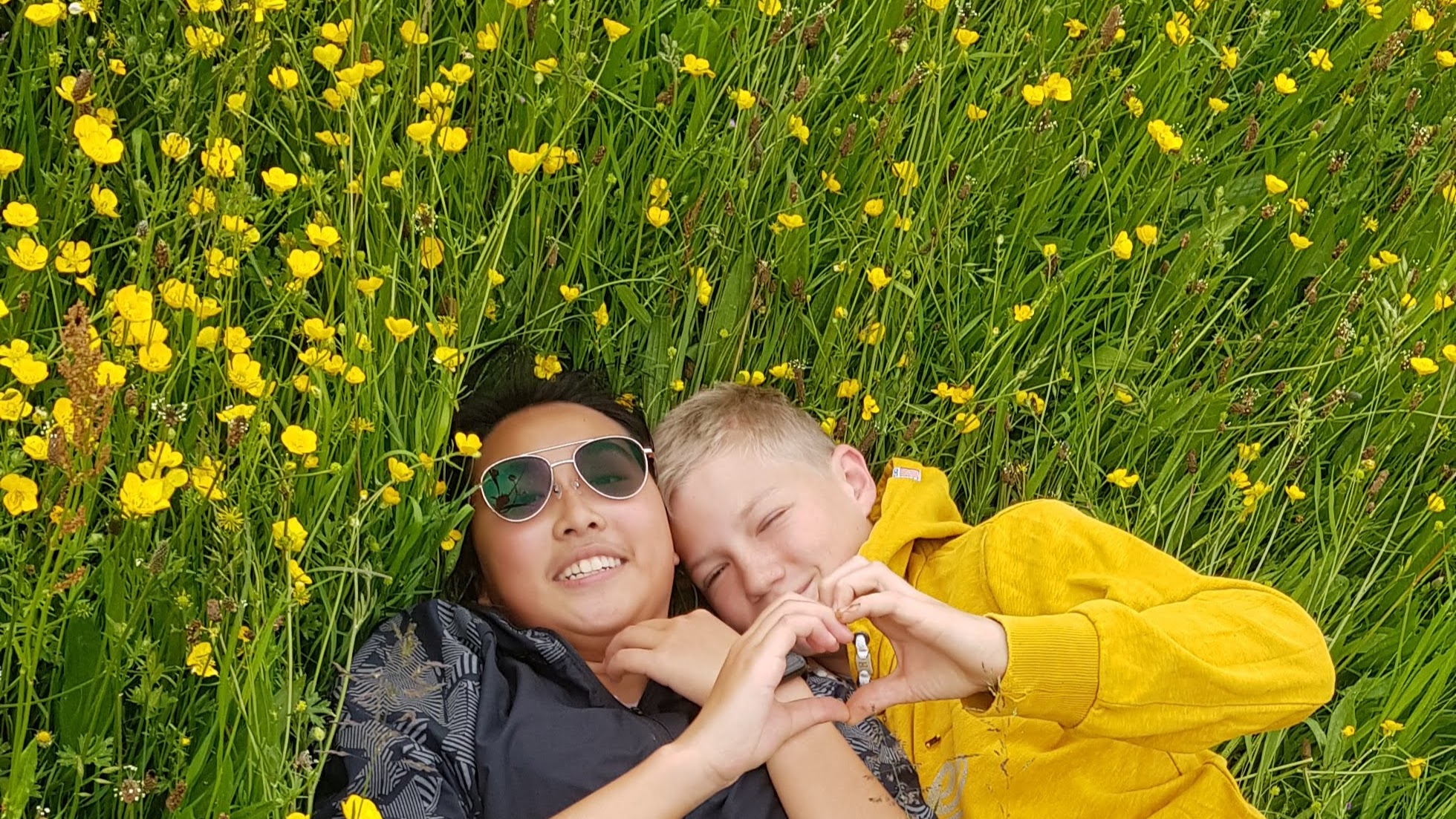 Sam de Hong Kong et Marin de France souriant ensemble, enveloppés dans les drapeaux de leurs pays — symbole d’amitié et de respect entre cultures