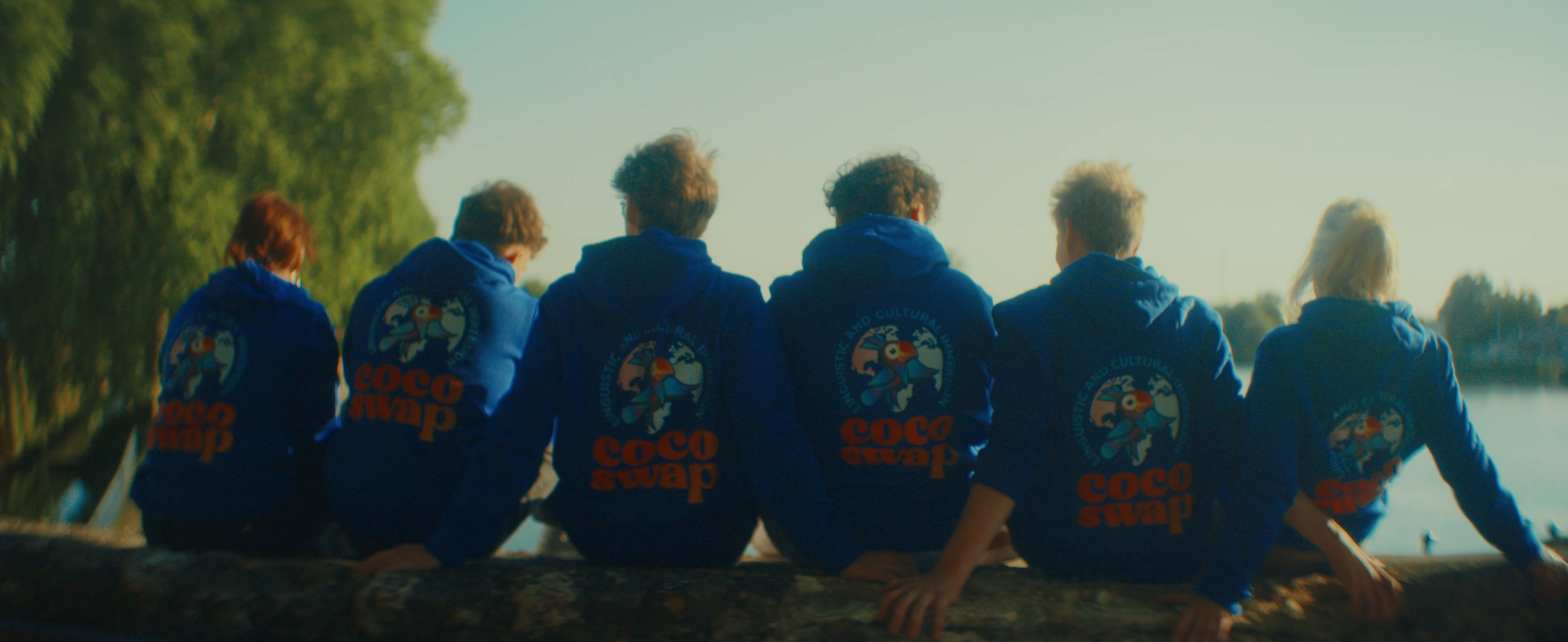 Deux jeunes amis allongés dans une prairie, formant un cœur avec leurs mains pendant un échange culturel